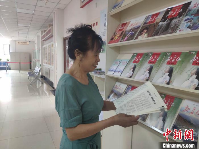 65歲的周云霞在社區(qū)看雜志打發(fā)時(shí)間?！∽T偉旗 攝